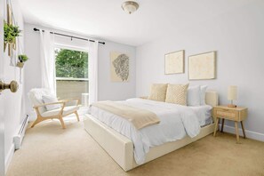 A bedroom with a bed, bedside tables, a chair, and artwork on the wall.