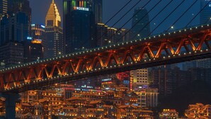 A bridge with illuminated lights spanning over a cityscape with traditional buildings and modern skyscrapers. - Chongqing Jetbear Hotel (Chongqing)