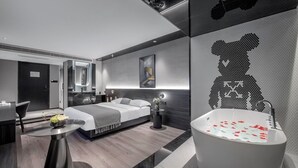 A modern hotel room with a large bed, a sitting area with a table, a large bathtub, and a wall art piece. - Chongqing Jetbear Hotel (Chongqing)