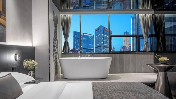 A modern hotel bathroom with a freestanding bathtub, a large window with curtains, and a city view. - Chongqing Jetbear Hotel (Chongqing)