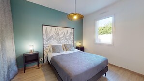 Una camera da letto con un letto, un comodino, una lampada a parete e una finestra vista verde.