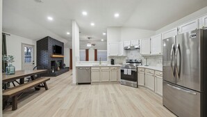 Una cocina moderna con armarios blancos, electrodomésticos de acero inoxidable y una mesa de comedor de madera.