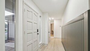 Un pasillo con puertas blancas, un radiador y un suelo de tonos claros.