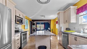 A modern kitchen with a central island, stainless steel appliances, and wooden flooring.