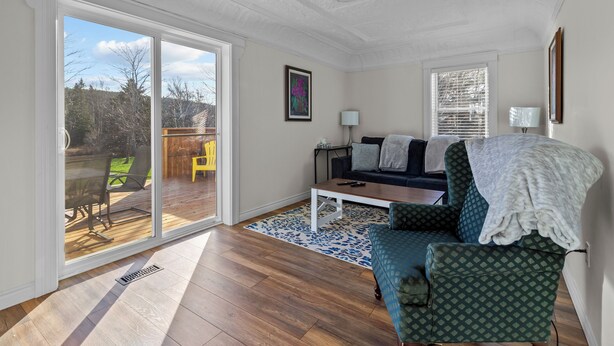 Een woonkamer met een schuifdeur naar een terras, een bank, een salontafel en een lamp.