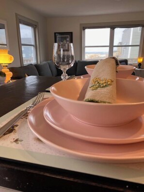 A dining table with a pink tablecloth, a glass of water, and a plate with a rolled-up napkin. - Elliston Oasis: Every View A Coastal Masterpiece (Elliston)