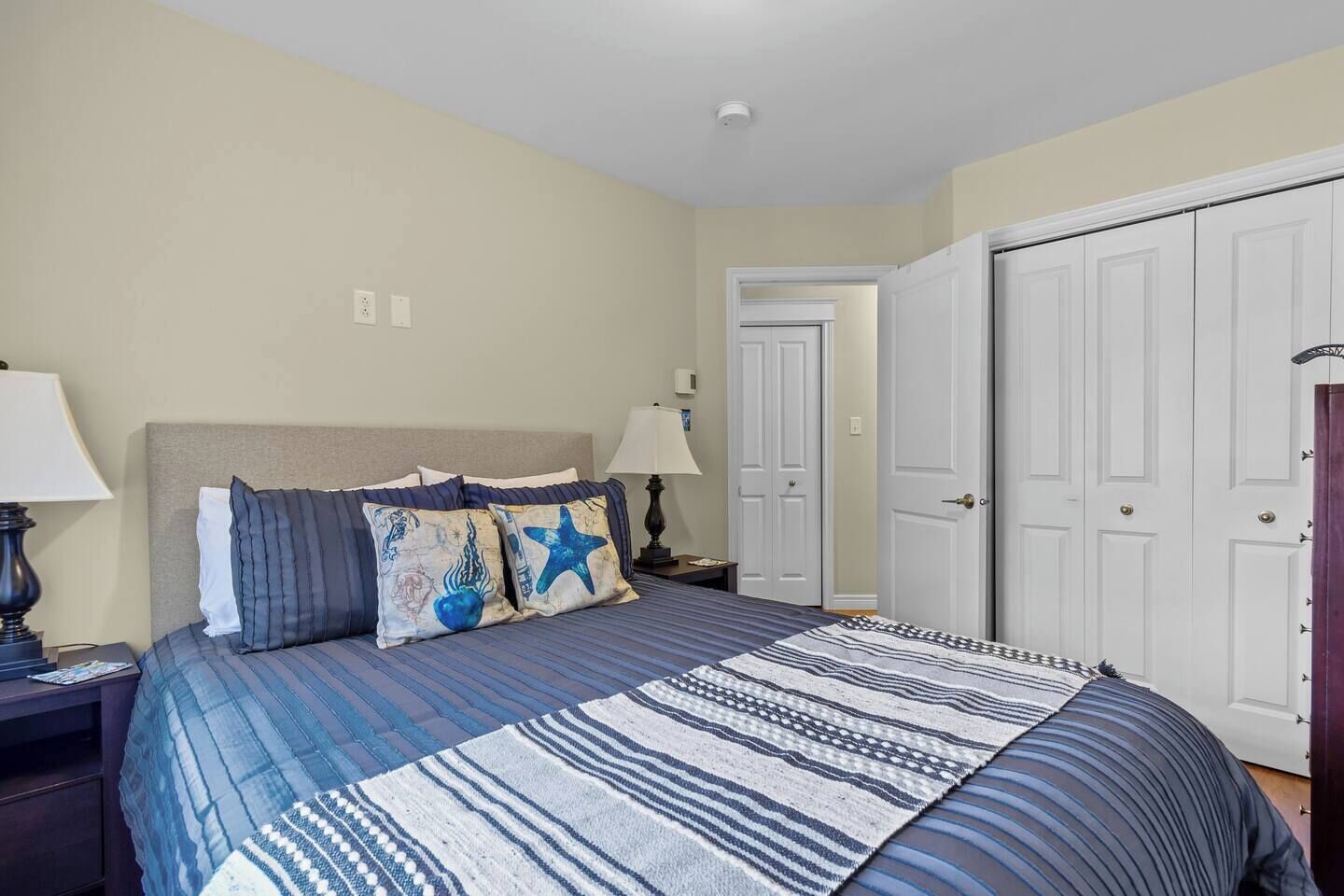 A bedroom with a bed, two nightstands, a lamp, a door, and a closet.