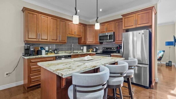 A modern kitchen with wooden cabinets, stainless steel appliances, and a central island with bar stools.