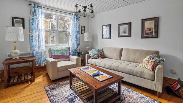 A living room with a sofa, armchair, wooden coffee table, and a patterned rug.