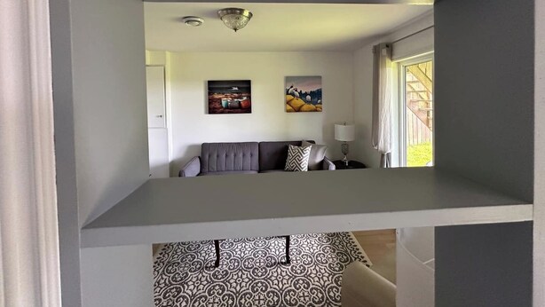 Ein Wohnzimmer mit grauem Sofa, einem gemusterten Teppich und zwei an der Wand befestigten Bildern.