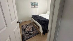 Ein Schlafzimmer mit Bett, Teppich, Gemälde und einer Tür.