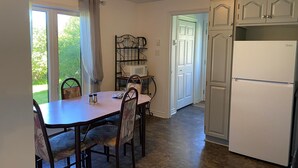 Eine Küche mit Esstisch, Stühlen, Kühlschrank und einer Mikrowelle auf einem Regal.