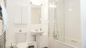 A modern bathroom with a toilet, sink, and glass-enclosed shower.