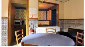 Comedor con una mesa, sillas, un extintor y una cocina al fondo.