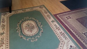 Amplia sala de estar con una escalera de madera, un espejo grande y una lámpara decorativa colgante.