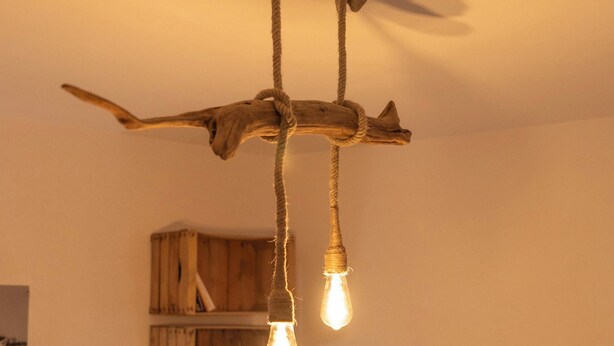 A rustic wooden ceiling with a light fixture hanging from a branch. - 🌿 Instant en Provence - LE GARDIAN Air-conditioned apartment in the heart of Alpilles (Eyragues)