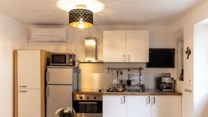 A modern kitchen with white cabinets, stainless steel appliances, a microwave, oven, and a coffee machine. - 🌿 Instant en Provence - LE GARDIAN Air-conditioned apartment in the heart of Alpilles (Eyragues)
