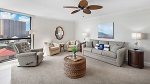 Ein modernes Wohnzimmer mit grauem Sofa, Sesseln, Couchtisch und Deckenventilator.