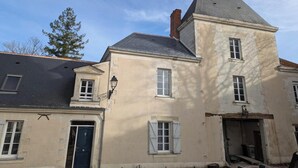 Un bâtiment à deux étages, doté d’une façade en pierre, de nombreuses fenêtres et d’un toit sombre.