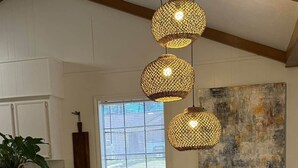 Een eethoek met een ronde tafel, vier stoelen en drie hangende lampen.