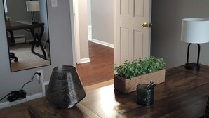 Una sala de conferencias con una mesa de madera, una silla de oficina negra, una lámpara, una planta en maceta y un espejo en la pared.