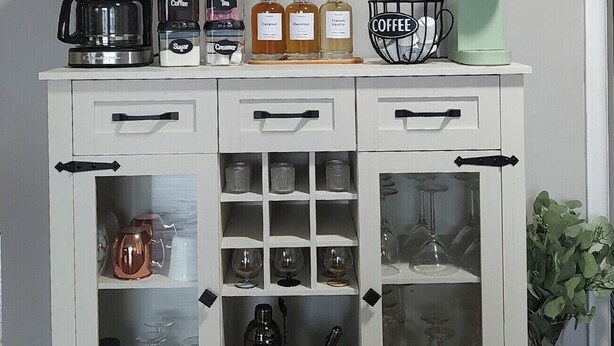 Una estación de café con cafetera, azúcar, leche y granos de café.