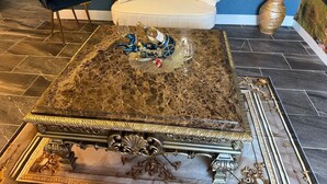 Una habitación lujosa con una mesa de centro de mármol, un sofá mullido y un jarrón decorativo.