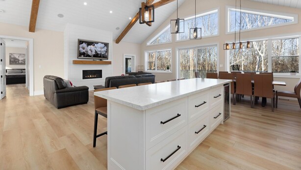 A spacious kitchen with a large island, wooden beams, and large windows.