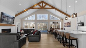A spacious living area with a fireplace, a large sofa, and a dining area with bar stools.