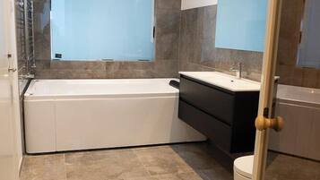 Un baño moderno con bañera, tocador y retrete.