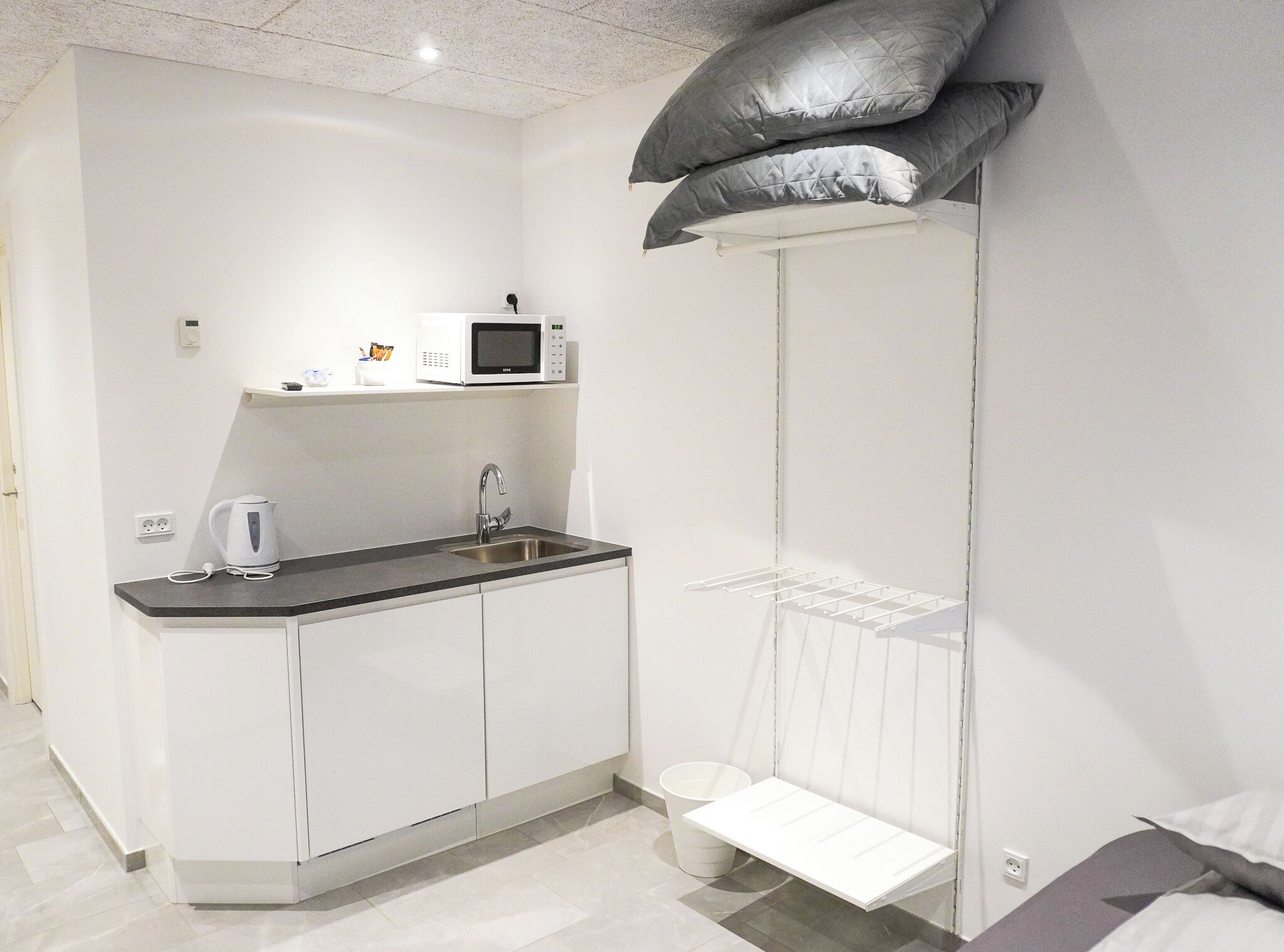 Una cocina moderna con microondas, hervidor y pileta.