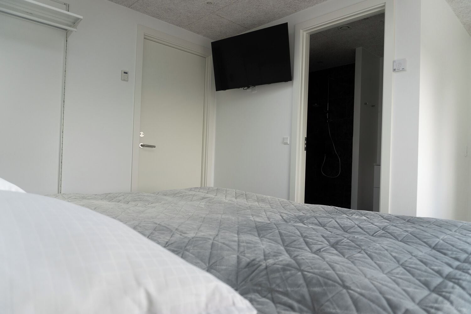 Un dormitorio con cama, puerta y zona de ducha.