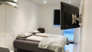 Una camera da letto con un letto, una TV a muro e una finestra.