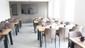 A modern conference room with multiple tables and chairs, a large screen, and a striped wall.