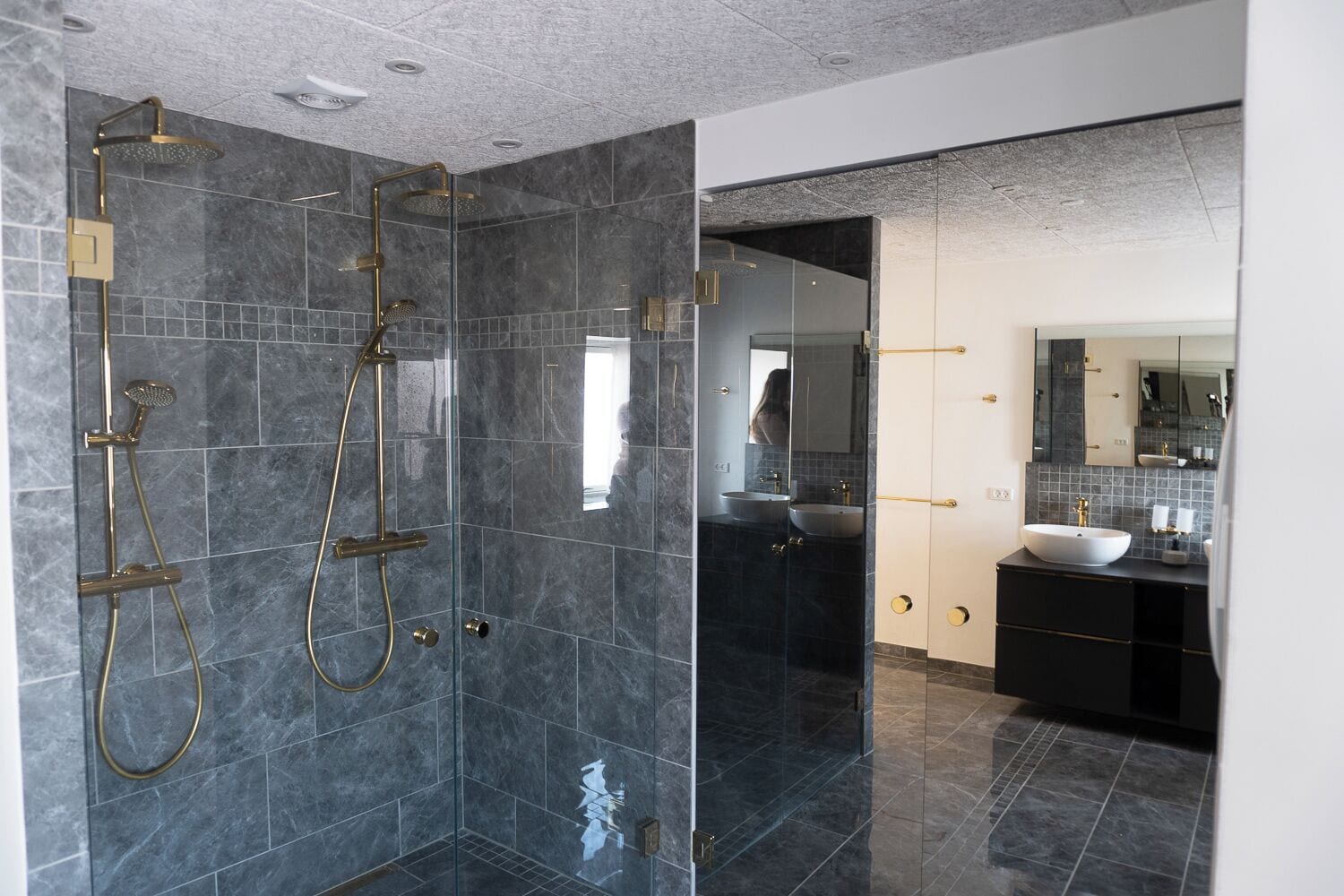 Un baño moderno con ducha de vidrio, tocador con lavabo y un espejo grande.