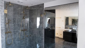 Un baño moderno con ducha de vidrio, tocador con lavabo y un espejo grande.