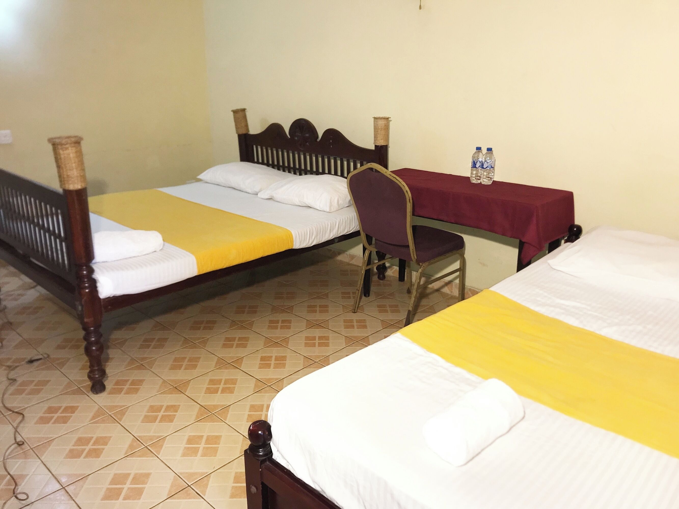 A room with two beds, a chair, and a table with water bottles.