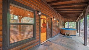 Une cabane en rondins dotée de grandes fenêtres, d’un jacuzzi et d’une véranda couverte.