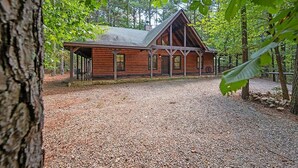 Un chalet rustique avec une allée en gravier, entouré d’arbres.