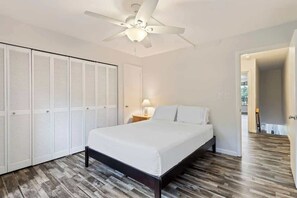 A bedroom with a bed, a ceiling fan, a wardrobe, and a nightstand with a lamp. - Partial Oceanview 2 bedroom condo, across st from ocean, walk to shops & dining (Napili-Honokowai)