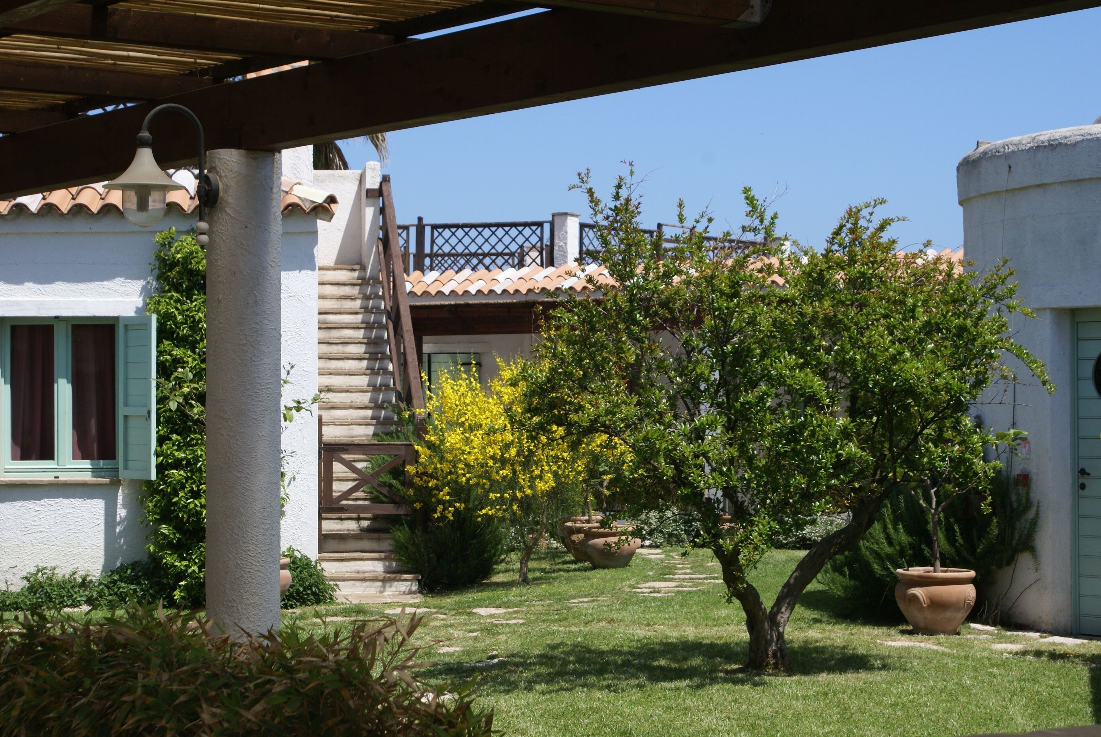 A courtyard with a staircase, a tree, and a building with a tiled roof.