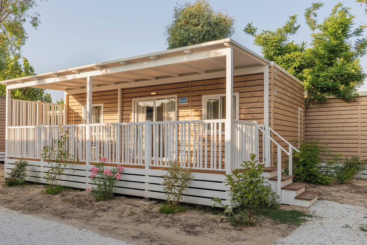 Une cabane en bois avec un porche couvert, une porte et une fenêtre.