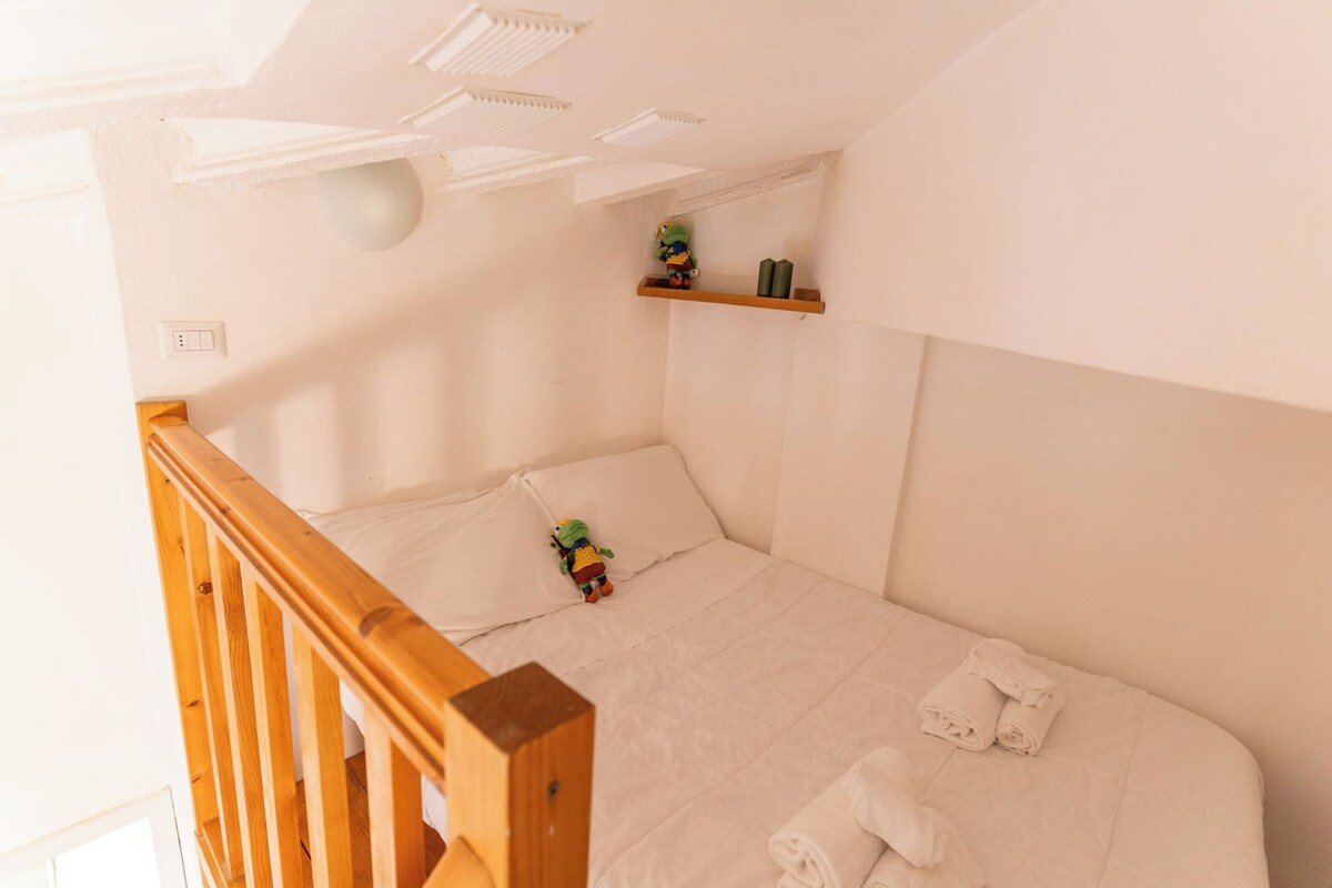 Ein kleiner, ordentlicher Raum mit einem Einzelbett, einem Holllaufgeländer, einer Ablage mit einem Spielzeug und einer Steckdose.