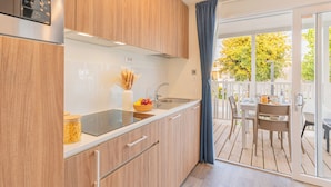 Una cocina moderna con armarios de madera, un lavamanos de acero inoxidable y una zona de comedor con mesa y sillas.