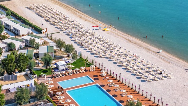 Un resort con varias piscinas, sombrillas de playa y gente disfrutando de la playa.