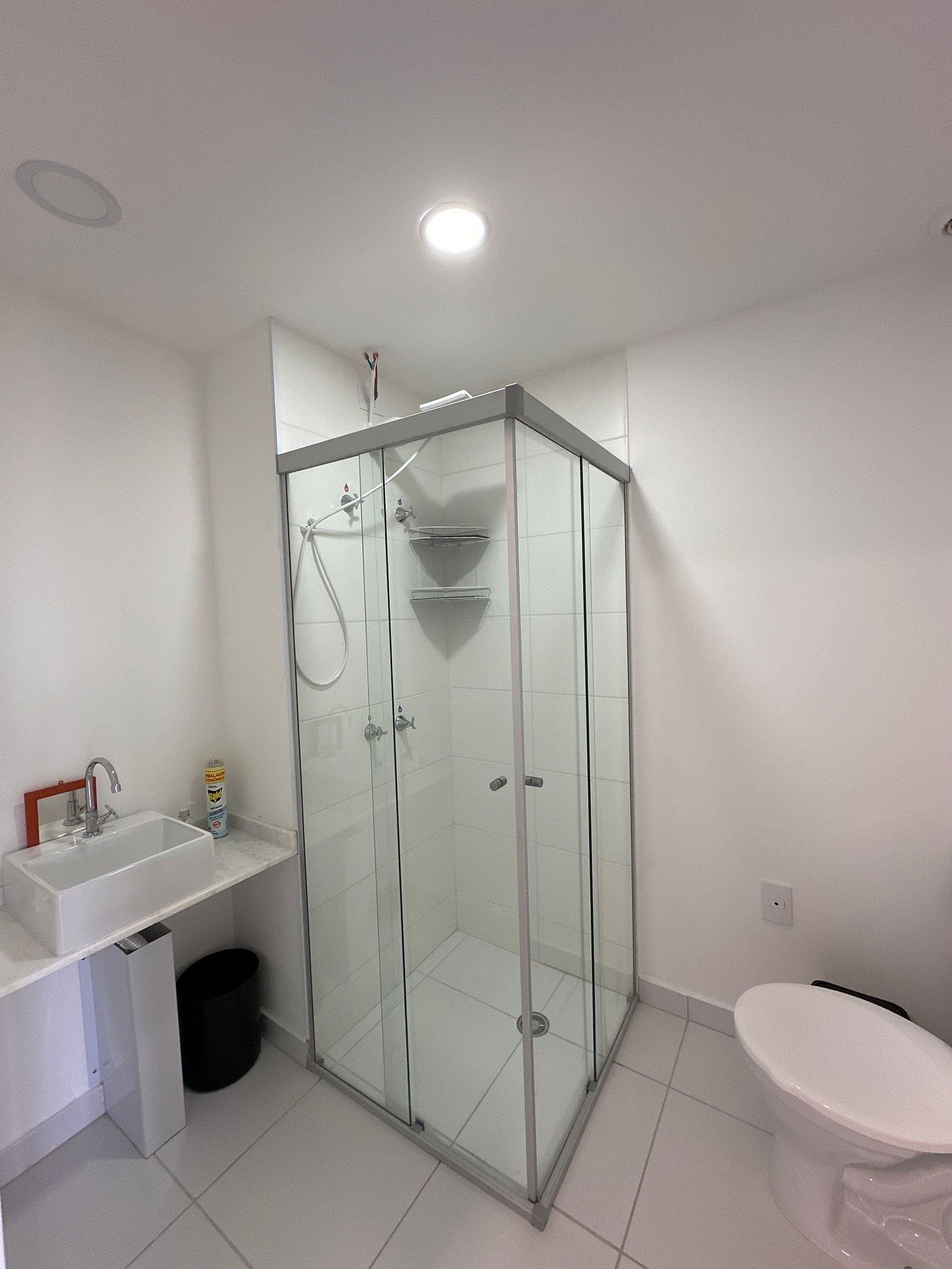 Ein Badezimmer mit einer Duschkabine, einem weißen Waschbecken und einer Toilette.