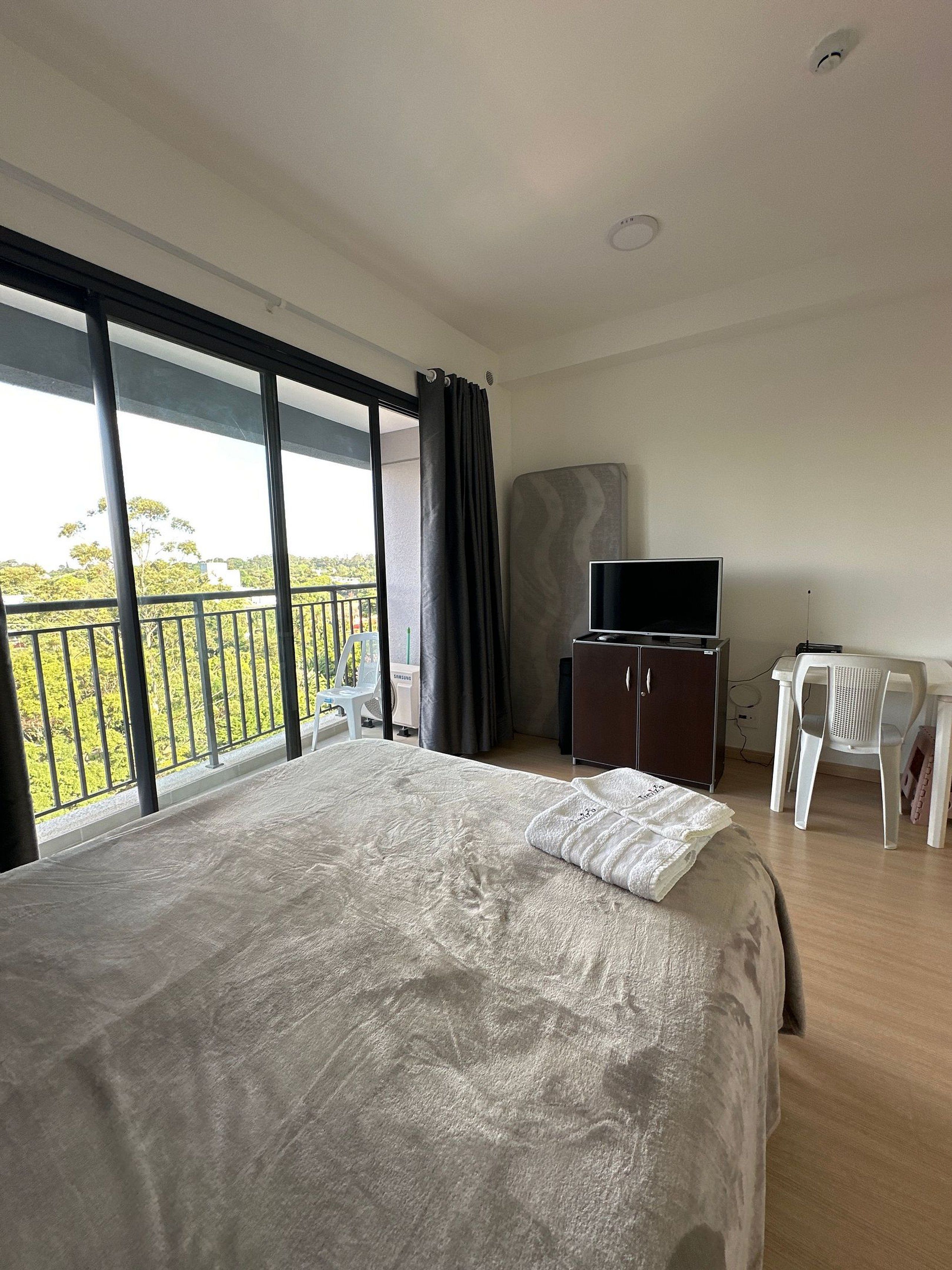 A bedroom with a bed, a TV, a desk, and a chair.