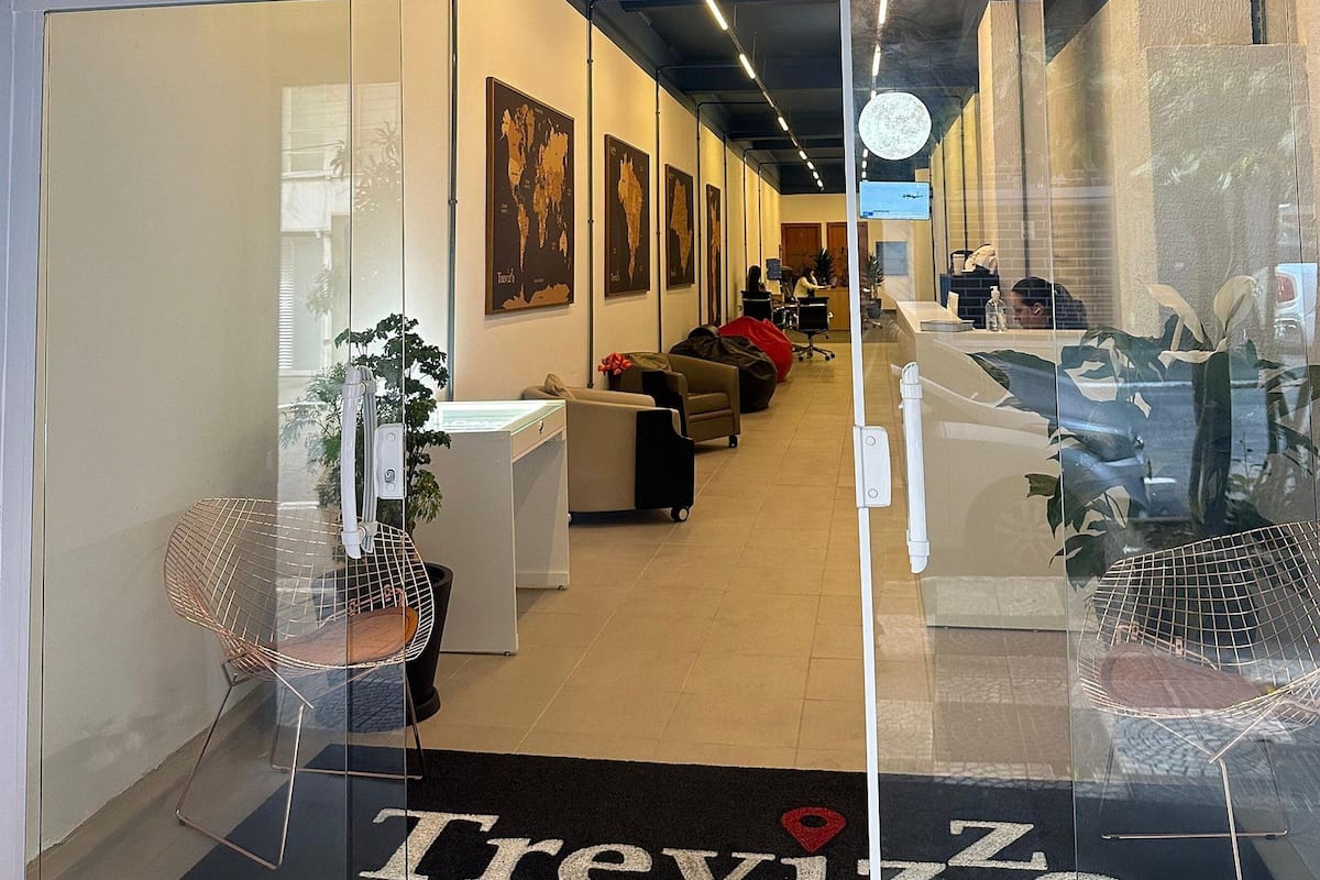 The entrance of a hotel named Treviso with a reception desk, seating area, and world maps on the walls.