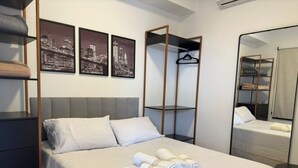 A neatly arranged hotel room with a bed, a wardrobe, a mirror, and three black-and-white cityscape photographs on the wall. - TrevizZo Borba Gato (São Paulo)