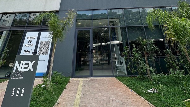A modern building with a glass entrance, a sign indicating a sale, and a number 599 sign. - TrevizZo Borba Gato (São Paulo)
